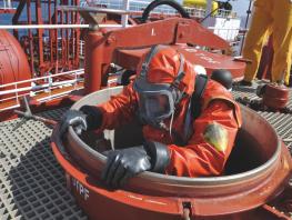 Person wearing protective suit and oxygen tank and mask descending down ship opening  