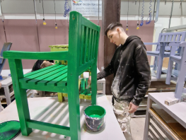 A student paints the hospice furniture. 