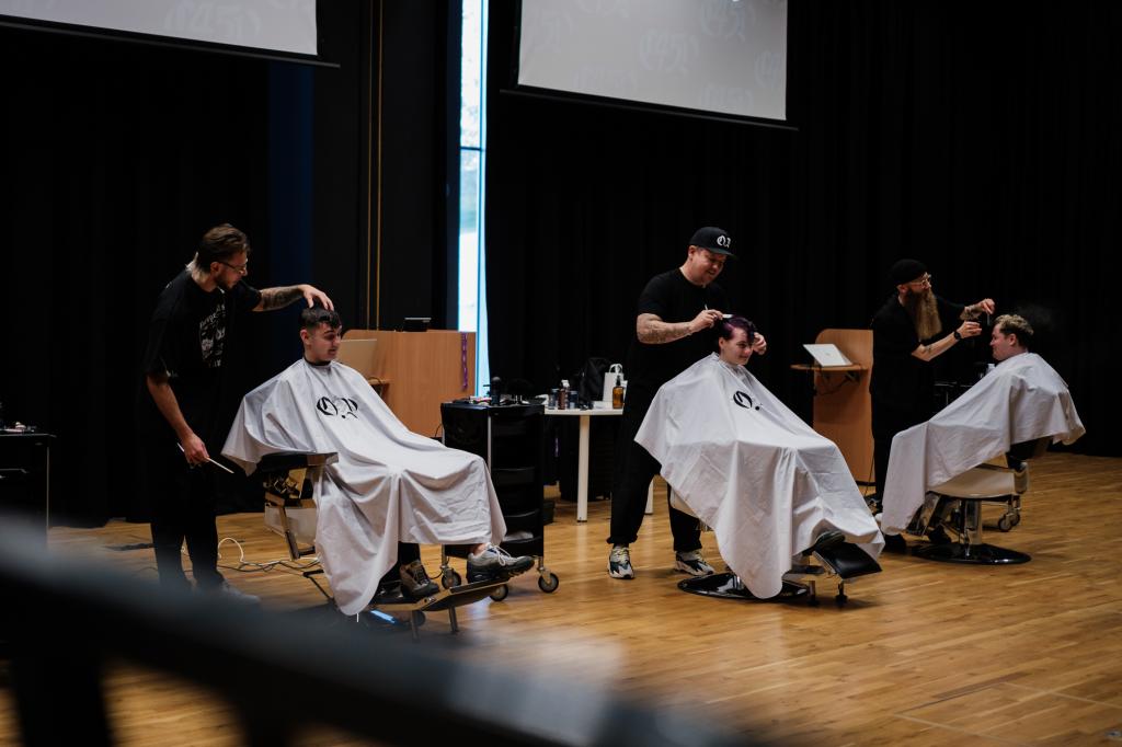 Barber.josh.o.p trainers demonstrating cutting techniques on stage at City campus