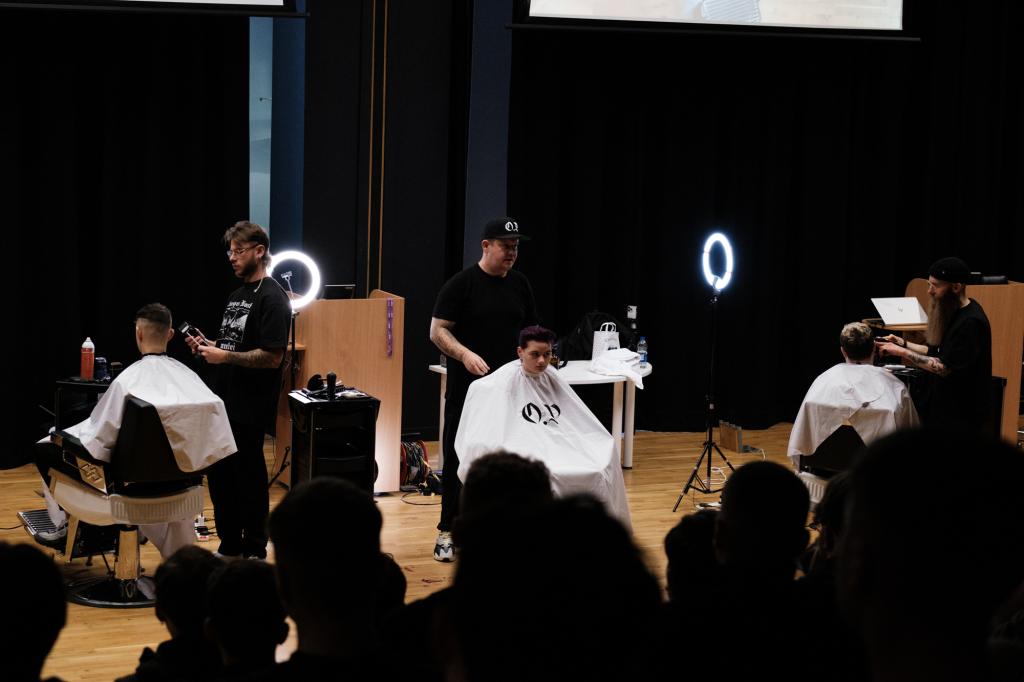 Barber.josh.o.p trainers demonstrating cutting techniques on stage at City campus