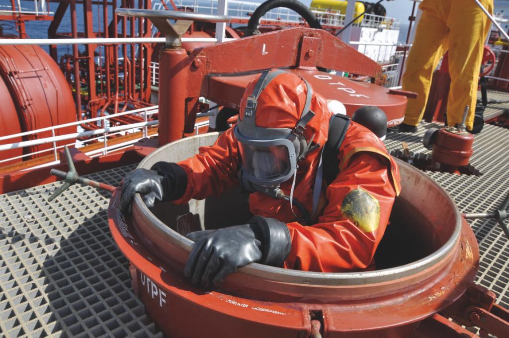 Person wearing protective suit and oxygen tank and mask descending down ship opening