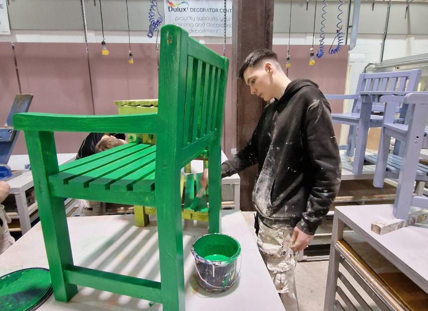 A student paints the hospice furniture.