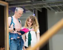 Student and guest at an open day reading a prospectus