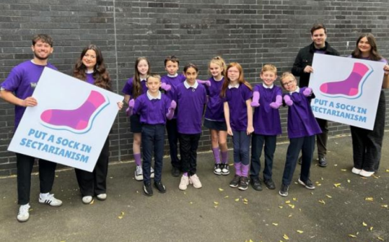 City students stand with Cairn Primary school children learning about their campaign (Image Nil by Mouth)