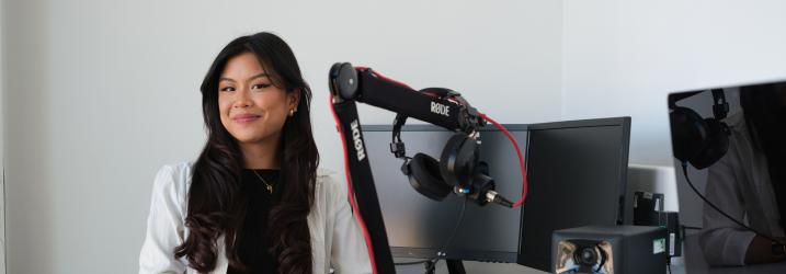 Marielle Reye sitting at a desk with a monitor and microphone on it.