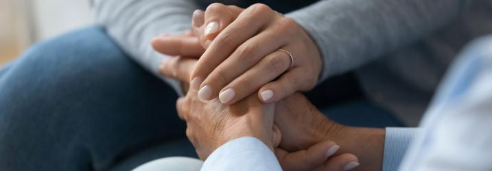 Close up of two people sitting holding hands