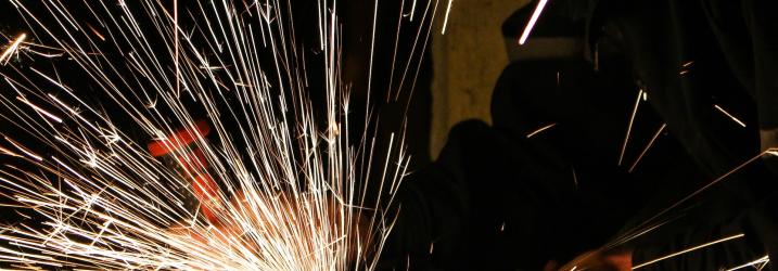 Student working with welding equipment and sparks.