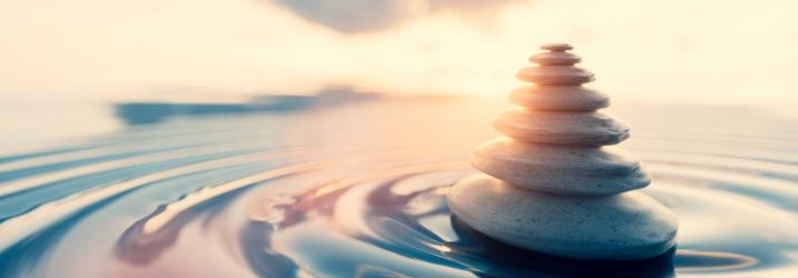 A pile of rocks in water with sunset in the background