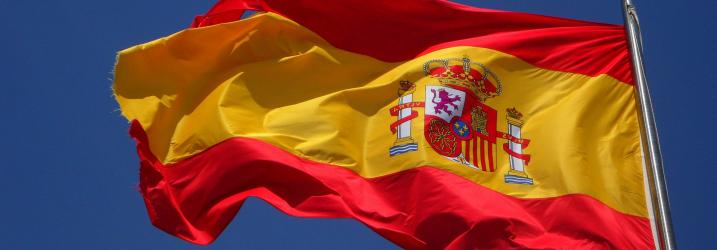 Spanish flag blowing in the wind with clear blue sky in the background.